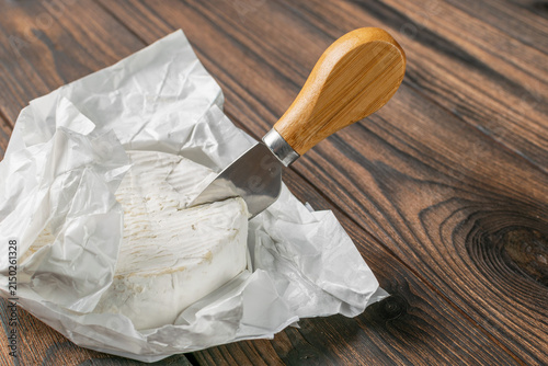 Foto Round Brie Cheese with Knife on Rustic Wooden Table: Gourmet Dairy Delight