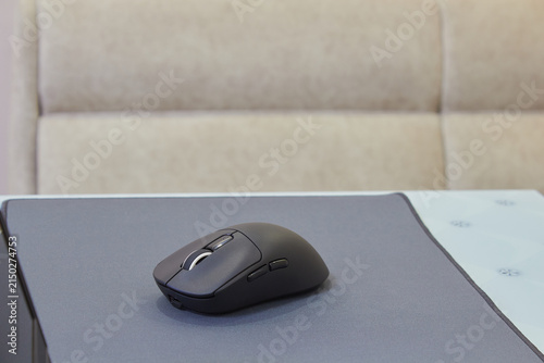 Quadro su tela Black wireless computer mouse on a gray rug, wireless ergonomic mouse for work,