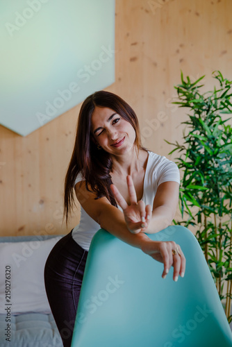 Foto Happy young woman laughing naturally while leaning over a turquoise chair in a b