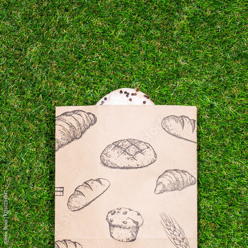 Freshly baked donuts and crumpled paper bag on a grass background .Top view.