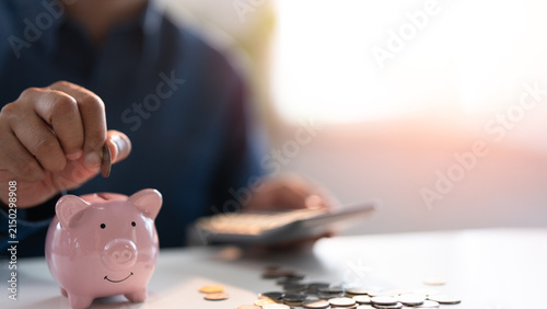 Hand putting coins into a pink piggy bank saving bank for account save money. Planning step up, saving money for future plan, retirement fund. Business investment-finance accounting concept.