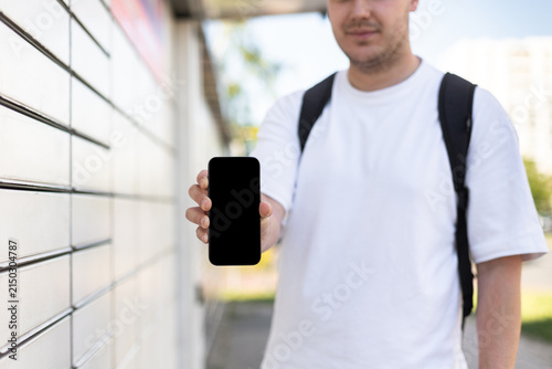 Photography A guy sends or receives a parcel at a parcel machine on the street using a smart