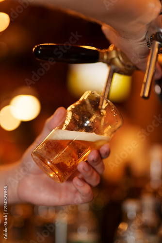 Принти на полотні Fresh draught beer is being poured into a clear glass.