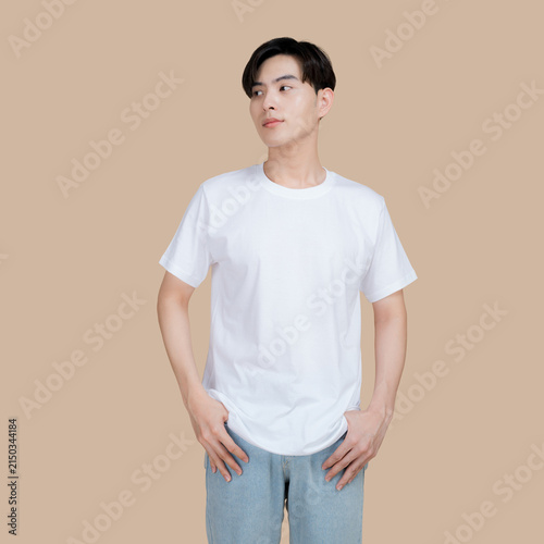 Young man in a plain white t-shirt and denim jeans posing against a neutral background