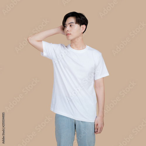 Young man in a white t-shirt and jeans posing against a neutral background