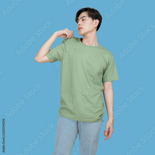 Young man in a green t-shirt and patterned pants posing against a blue background