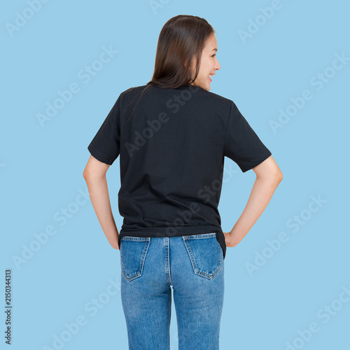 Young woman in black t-shirt and blue jeans standing with hands on hips