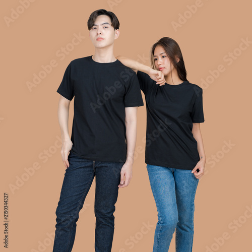 Young Asian couple in matching black t-shirts and jeans posing against a neutral background