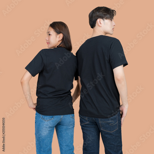 Young couple wearing plain black t-shirts and denim jeans standing back to back