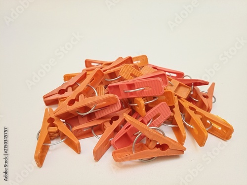 A pile of orange laundry clips on the white background, plastic clothes pins or clothes pegs for house