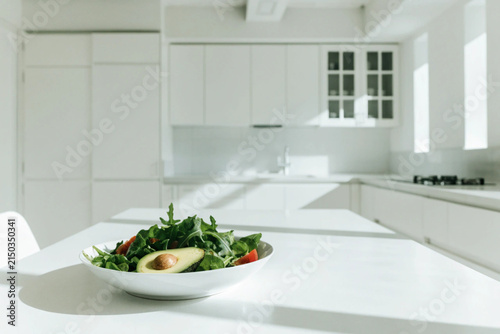 Fresh avocado, tomatoes, salad in white bowl on the white table in the white modern kitchen. Copy space