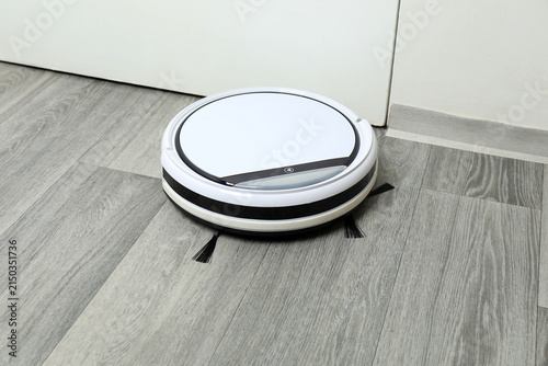 Robotic vacuum cleaner on laminate floor in living room. Smart cleaning technology.