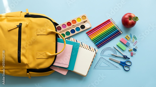 Colorful school supplies arranged on a light blue surface with a brown backpack