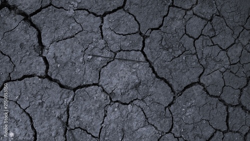 Quadro su tela Dark monochrome cracked earth texture with large irregular fractures and rough dry soil, representing drought, environmental change, erosion, and arid landscapes