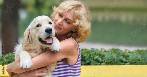 Konstfotografi Woman hugging beloved Golden Retriever puppy outdoors in city park