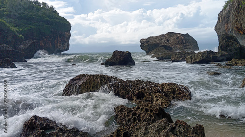 Ocean waves crashing over rough coral rocks on a tropical rocky beach landscape background