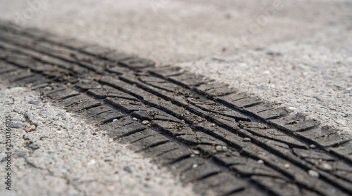 Abraded tire tread imprint marking asphalt signifying kinetic energy transfer and automotive motion on rough terrain conveying a sense of powerful acceleration and braking.
