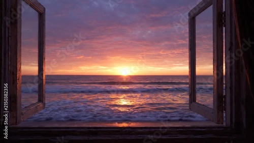 Beautiful sunset view over ocean waves seen through open window frame