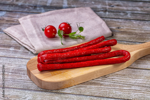 Фотография Mini salami on wooden cutting board with cherry tomatoes and linen napkin