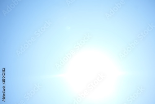 Fotografie Bright sun flare in clear blue sky background copy space
