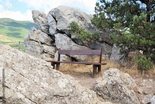 A summer mountain landscape. A wooden bench stands high in the mountains.