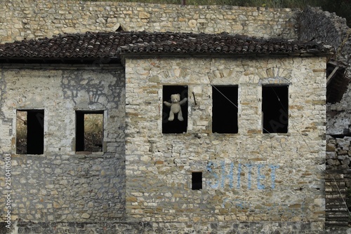 Abandoned building in Berat Castle, Albania, with a teddy bear in a window, loss and forgotten childhood