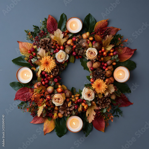 Autumn wreath with flowers and candles on gray background  