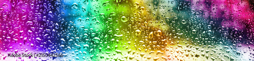 Raindrops on a window create colorful patterns in a bright setting during the day