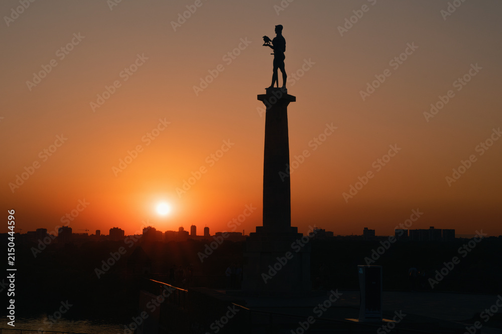 Fototapeta premium Belgrade, Serbia - August 4, 2026:Silhouette of the Pobednik monument and the city with a beautiful sunset...