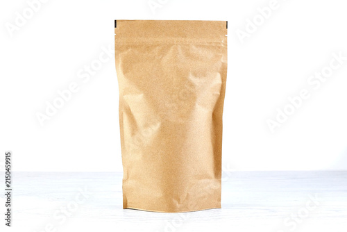 Blank brown kraft stand up pouch with natural paper texture and subtle wrinkles isolated on a white background for food and product packaging presentation.