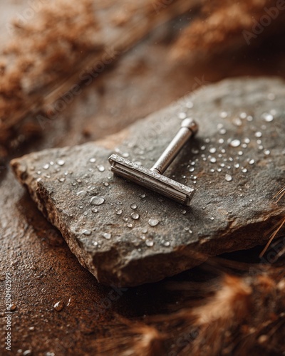 Unbranded safety razor on a stone slab, tiny water droplets, soft diffused light, premium minimal still life