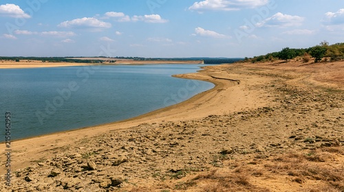 wide landscape photograph of a depleted freshwater reservoir with a clearly visible low-water shoreline