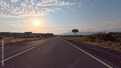 Sunset view of straight road with white lines