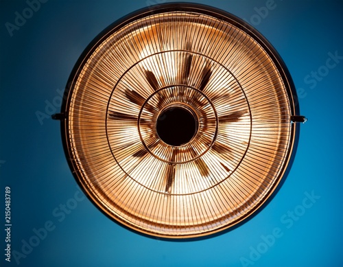 a close up shot of a circular light fixture against a blue backdrop