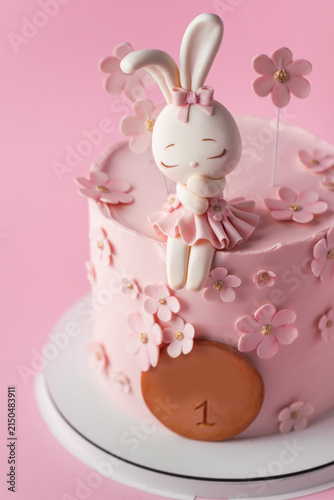 Cute pink bunny themed first birthday cake with cherry blossom decorations on the pink background