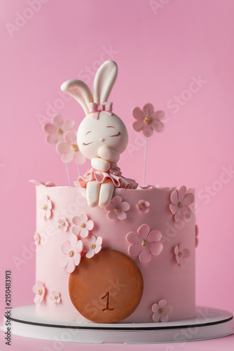 Cute pink bunny themed first birthday cake with cherry blossom decorations on the pink background