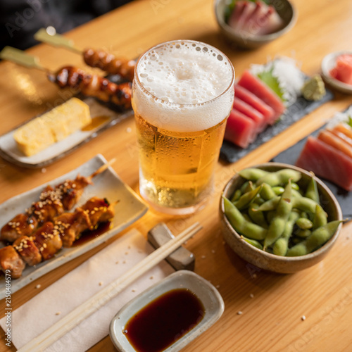 Overhead view of assorted Japanese izakaya small dishes and beer