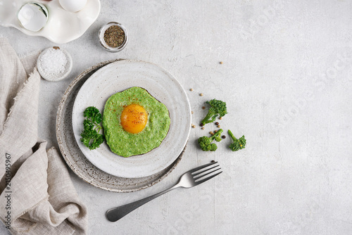 Fried egg in broccoli puree ring on plate with copy space. Healthy breakfast horizontal top view.