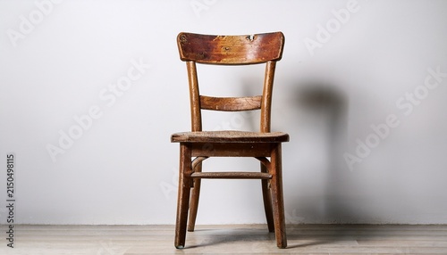 an old wooden chair with a worn seat and backrest standing alone against a plain white background