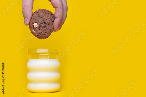 Obraz na płótnie Chocolate chip cookie positioned above a white milk jar on a yellow studio background