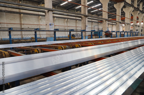 Aluminum extrusion production line inside large industrial workshop, factory manufacturing scene