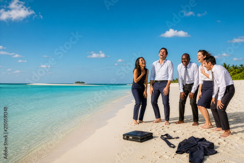 An image representing positive business teamwork and work-life balance. Businesspeople laughing heartily while barefoot on an uninhabited island. Copy space