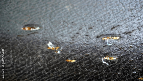 Cuadro en lienzo Close-up of torn black leather surface showing damaged holes and frayed white threads