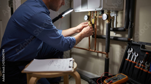 Plumber performs preventive maintenance on tankless water heater, adjusting valves and documenting service findings to support plumbing safety, home maintenance and efficient hot water systems.