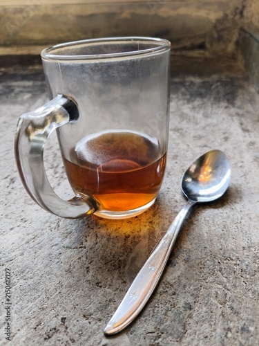 фотографія A glass of hot tea in a white glass mug with a spoon