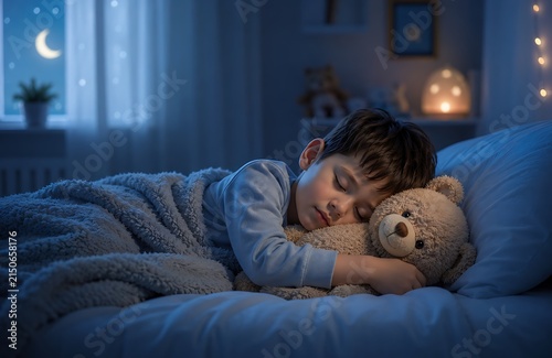 Little boy sleeping peacefully in dark bedroom hugging plush teddy bear toy at night.