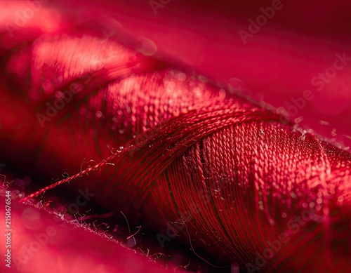 A macro shot of a spool of vibrant red thread.