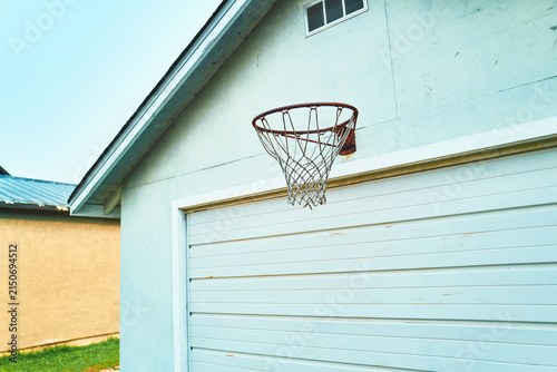 Rusty basketball hoop with torn net mounted on a garage wall