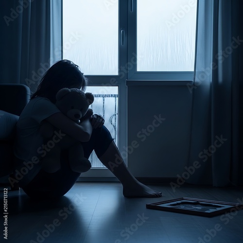 Sad Woman Sitting Alone in Dark Room Holding Photo Frame.