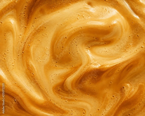 Abstract macro texture of swirling golden brown whipped coffee foam